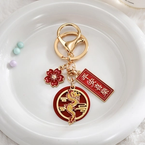 Detail of dragon keychain with Peace and Joy charms and cherry blossom pendant