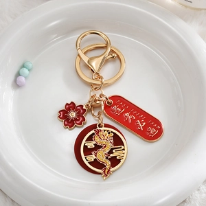 Close-up of golden dragon keychain with red lucky charm and academic success engraving