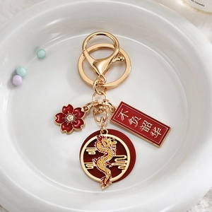 Detail of golden Chinese dragon keychain with red enamel charms on a ceramic plate