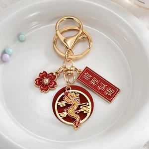 Close-up of a festive Chinese dragon keychain with a lucky pendant and red floral charm