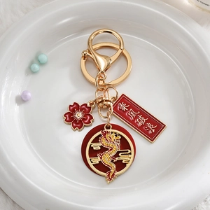 Chinese dragon keychain with gold ring, red enamel flower and lucky charms on white plush