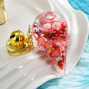 Macro detail of pink acrylic ice cream keychain with floating sequins and gold bell