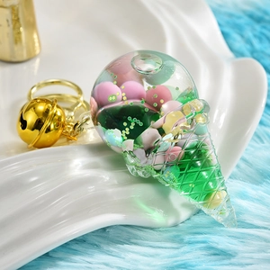 Detail of acrylic ice cream keychain with floating beads, green liquid and gold bell accessory