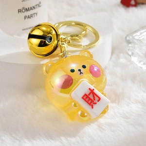 Macro detail of jelly bear keychain with mahjong fortune charm and golden bell