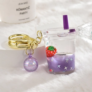 Macro shot of liquid glitter keychain with purple strawberry in acrylic cup