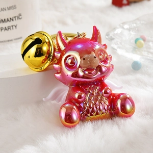 Close-up of pink gradient metal dragon keychain with a large gold bell on plush decor