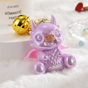 Pearly purple dragon mascot keychain with large gold bell and wings on white plush mat