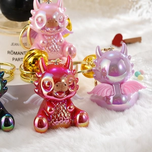 Charming dragon mascot keychains in assorted pearlescent colors on a white plush background