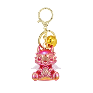 Cartoon dragon mascot keychain with pearlescent purple finish and golden bell detail