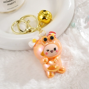 Détail d'un porte-clés grenouille rose nacré avec clochette dorée sur fond doux