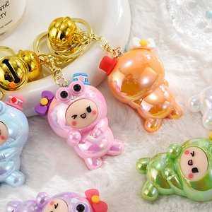 Détail de porte-clés grenouilles irisés colorés avec clochettes dorées sur peluche