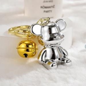 Macro shot of a chrome silver violent bear keychain with golden bell on white fur