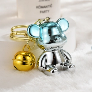 Macro detail of gradient blue and silver metallic bear charm with a golden bell