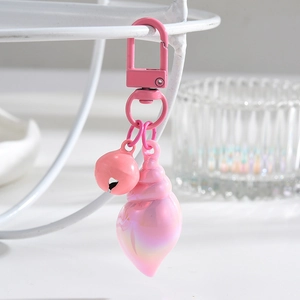 Macro view of a pink iridescent seashell keychain with a small bell and metal carabiner
