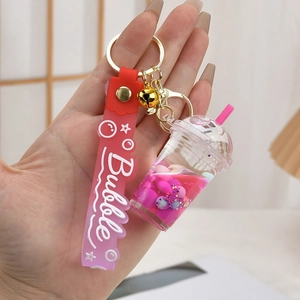 Pink bubble tea keychain with liquid, gold bell, and gradient silicone wrist strap