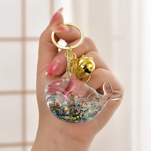 Detailed close-up of whale keychain with colorful stars and a golden bell accessory