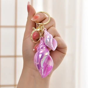 Iridescent conch shell keychain in purple and pink tones with golden metal lobster clasp