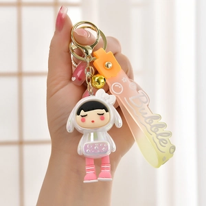 Detailed view of cute girl doll keychain with pink gradient strap and golden bell charm