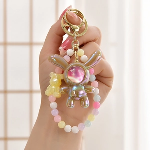 Macro shot of iridescent astronaut rabbit keychain with colorful beads and gold clasp
