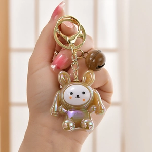 Macro view of pearlescent rabbit keychain with golden metal hardware and a small bell