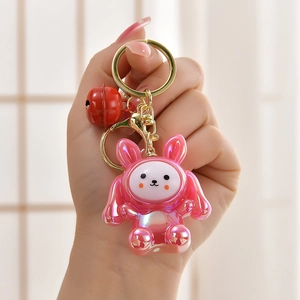 Detailed close-up of a pink pearlescent rabbit keychain with golden metal ring and bell