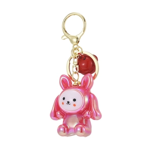 Pink rabbit keychain with golden metal clasp and a red bell on white background