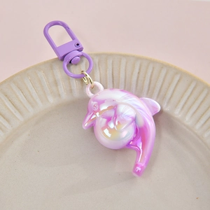 Cute gradient pink purple dolphin keychain with iridescent coating in a ceramic tray