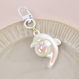 Cute iridescent dolphin acrylic keychain pendant with pearl finish on a ceramic plate