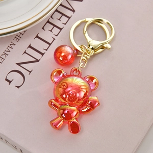 Detail of gradient red acrylic bear keychain with gold clasp on aesthetic background