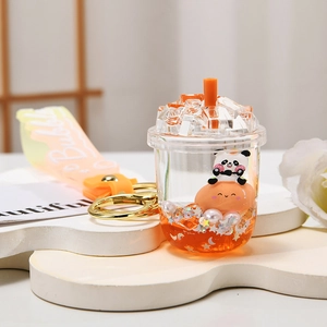 Close-up of cute panda figurine inside an orange bubble tea quicksand keychain with liquid