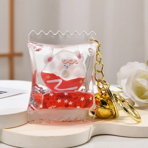 Detailed macro view of liquid quicksand acrylic keychain with white cartoon figure and gold bell