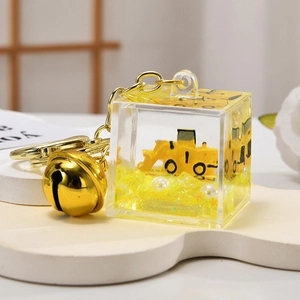 Detailed close-up of a cube acrylic keychain featuring a yellow excavator and white pearls
