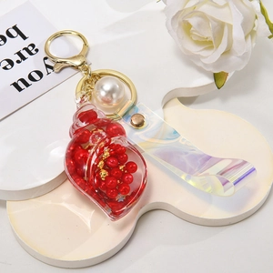 Detail of red shell keychain with white pearl and holographic PVC strap on display