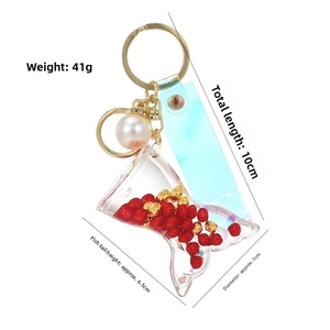 Detail view of mermaid tail keychain with red beads and laser rainbow strap