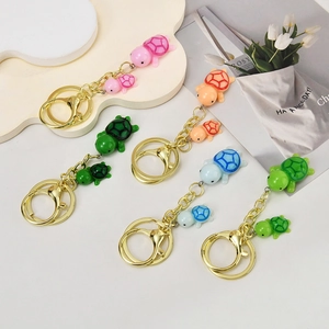 Close-up of colorful resin mother and child turtle keychains with golden alloy clips