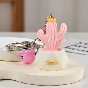 Detailed close-up of a pink resin cactus keychain with a white Smile pot and pink bell