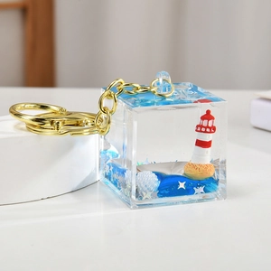 Detail of nautical keychain with lighthouse, blue liquid and sequins in acrylic cube