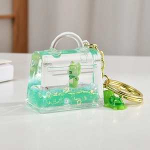 Detail of green fox acrylic quicksand keychain with liquid glitter and turtle charm