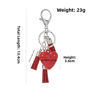 Macro detail of red heart keychain with silver lobster clasp and leather tassels