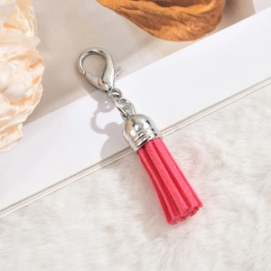 Detailed view of magenta suede tassel pendant with silver metal clasp and cap for bags