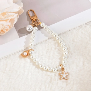 Elegant pearl chain keychain with gold starfish and shell pendants on plush background