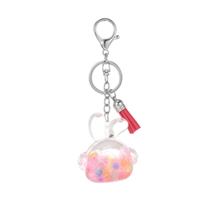 Cute bunny liquid oil keychain with colorful glitter sand and red tassel on white background