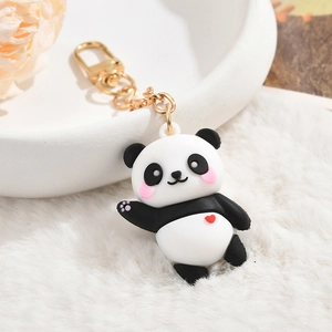 Detail of cute panda keychain with red heart and gold clasp on soft white fur backdrop