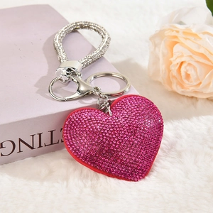 Close-up of a pink heart-shaped rhinestone keychain on white fluffy plush background