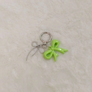 Close-up of a green resin bow and silver wire butterfly pendant on white fur