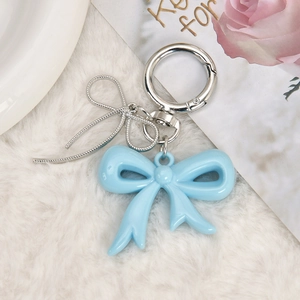 Close-up of light blue acrylic bow pendant with silver buckle on white plush background