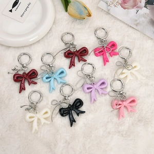 Acrylic ribbon bow keychains in various colors with metallic ring on a soft white background