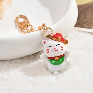 Close-up of Maneki-neko lucky cat keychain with red hat and golden bell accessory