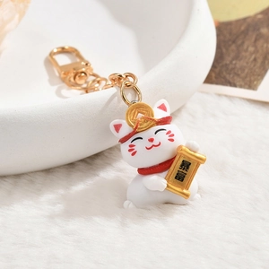 Cute lucky cat keychain with gold coin and scroll on a soft white plush background