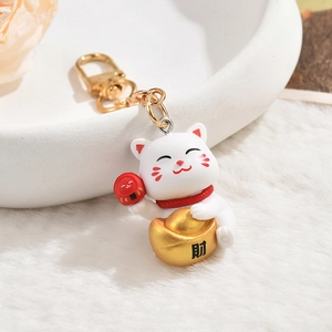 Cute white Maneki Neko keychain with golden ingot and red Daruma on white plush